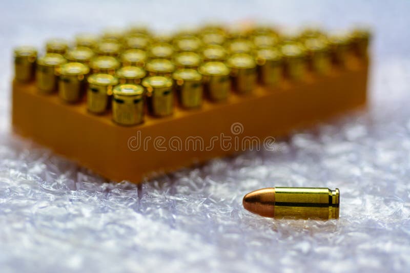 Copper Gun Bullet with Blurred Pistol on Natural Light Stock Image