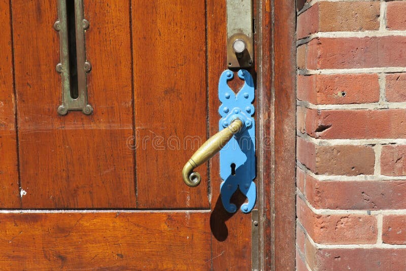 Copper Door Handle with a Blue Fitting on a Wooden Door Stock Image