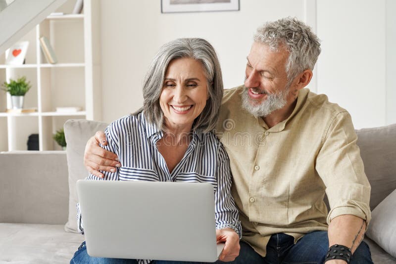 Coppia di medie e mature felici che fa commercio elettronico utilizzando il laptop a casa. immagini stock libere da diritti