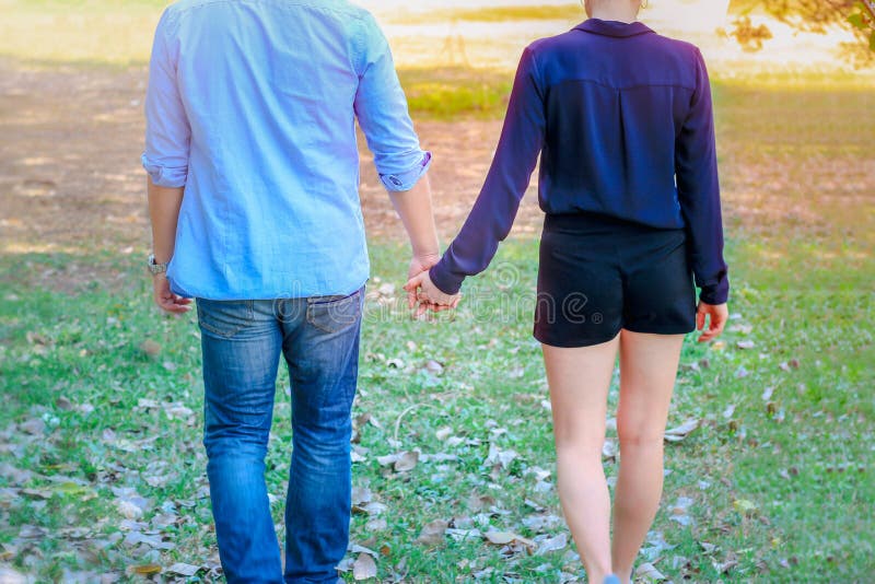 Coppia dolce che si tiene per mano mentre si rilassano e passeggiano nel parco giovani bellissimi amanti che passano del tempo ins fotografia stock