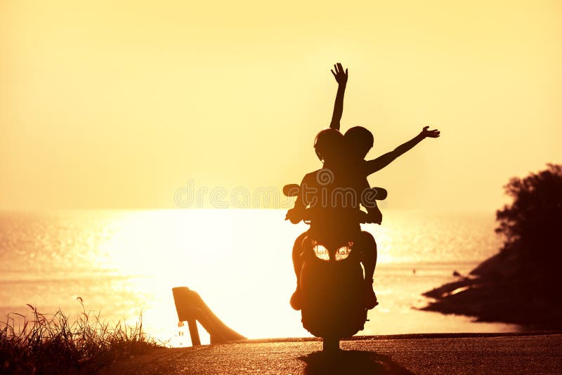 Coppia irriconoscibile sullo scooter contro il mare del tramonto immagini stock libere da diritti Coppia irriconoscibile sullo scooter contro il mare del tramonto immagini stock libere da diritti