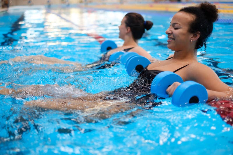 Coppia multirazziale che frequenta corsi di aerobica in una piscina