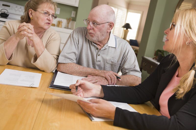 Coppie adulte senior che superano le carte nella loro casa con l'agente fotografie stock libere da diritti Coppie adulte senior che superano le carte nella loro casa con l'agente fotografie stock libere da diritti