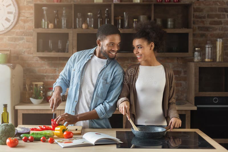 Coppie afroamericane amorose che preparano pasto nella cucina del sottotetto fotografia stock libera da diritti Coppie afroamericane amorose che preparano pasto nella cucina del sottotetto fotografia stock libera da diritti