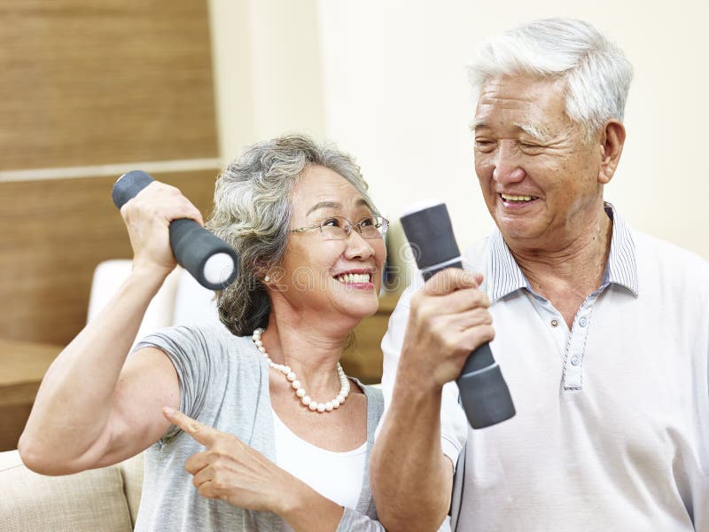 Happy senior asian women holding dumbbell showing her muscle to husband. Happy senior asian women holding dumbbell showing her muscle to husband