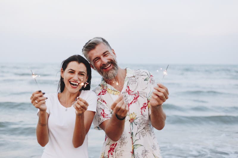 Coppie che celebrano con le scintille alla spiaggia fotografie stock libere da diritti Coppie che celebrano con le scintille alla spiaggia fotografie stock libere da diritti