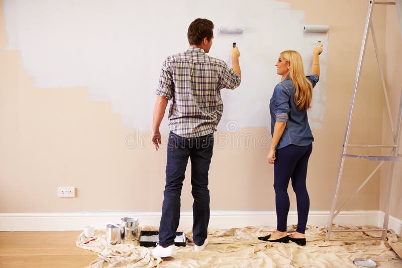 Coppie che decorano stanza facendo uso dei rulli di pittura sulla parete fotografia stock libera da diritti Coppie che decorano stanza facendo uso dei rulli di pittura sulla parete fotografia stock libera da diritti