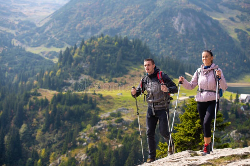 Coppie che fanno un'escursione nella montagna e che godono della vista sul lago immagini stock Coppie che fanno un'escursione nella montagna e che godono della vista sul lago immagini stock