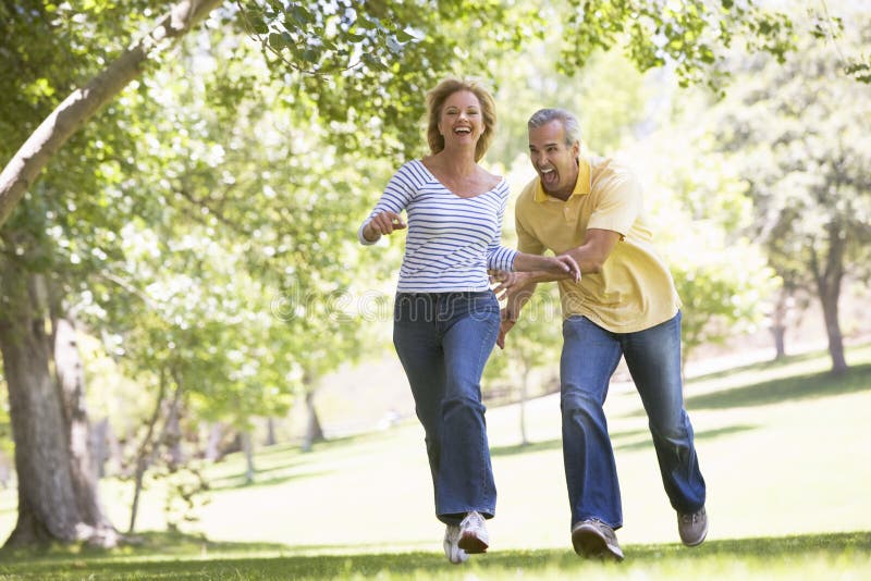 Coppie che funzionano all'aperto nella sosta e nel sorridere fotografia stock Coppie che funzionano all'aperto nella sosta e nel sorridere fotografia stock