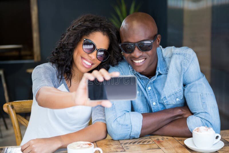 Coppie che prendono selfie con lo Smart Phone in caffetteria fotografie stock libere da diritti Coppie che prendono selfie con lo Smart Phone in caffetteria fotografie stock libere da diritti