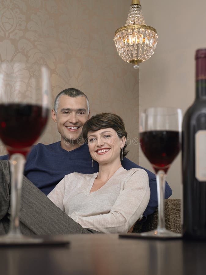 Coppie che si siedono su Sofa In Front Of Wineglasses immagini stock libere da diritti