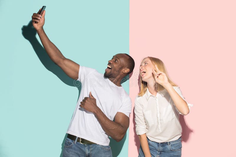 Coppie corse miste degli studenti che prendono selfie comune con il telefono Ragazza caucasica e suo il ragazzo africano che posa fotografia stock Coppie corse miste degli studenti che prendono selfie comune con il telefono Ragazza caucasica e suo il ragazzo africano che posa fotografia stock