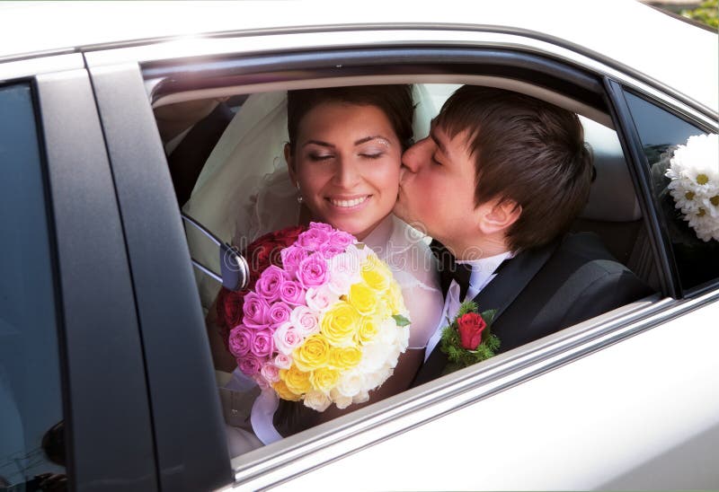 Coppie del Newlywed che baciano in automobile di cerimonia nuziale fotografia stock Coppie del Newlywed che baciano in automobile di cerimonia nuziale fotografia stock