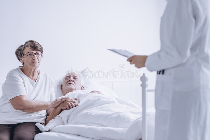 Couple of hopeful senior people listening to the doctor talking about test results. Couple of hopeful senior people listening to the doctor talking about test results