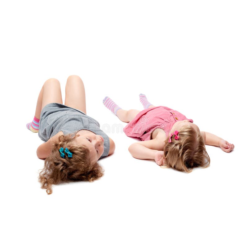 Coppie di giovani bambine che si trovano sopra il fondo bianco isolato fotografie stock Coppie di giovani bambine che si trovano sopra il fondo bianco isolato fotografie stock