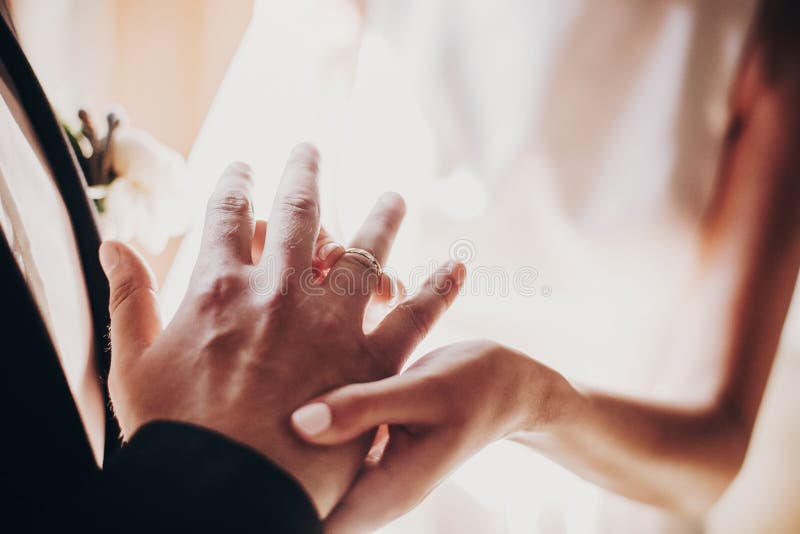 Wedding couple exchanging wedding rings during holy matrimony in church. Bride and groom putting golden rings on finger, close up. Spiritual moment. Wedding couple exchanging wedding rings during holy matrimony in church. Bride and groom putting golden rings on finger, close up. Spiritual moment