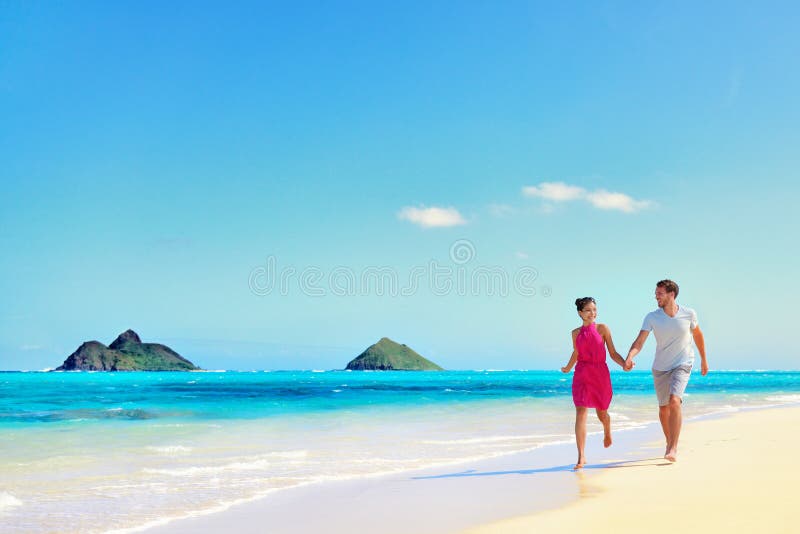 Coppie di vacanza delle Hawai che camminano sulla spiaggia del turchese fotografia stock libera da diritti Coppie di vacanza delle Hawai che camminano sulla spiaggia del turchese fotografia stock libera da diritti