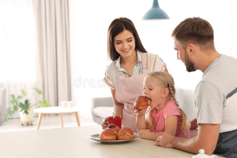Coppie felici che curano di recente la loro figlia con il panino al forno del forno fotografia stock Coppie felici che curano di recente la loro figlia con il panino al forno del forno fotografia stock