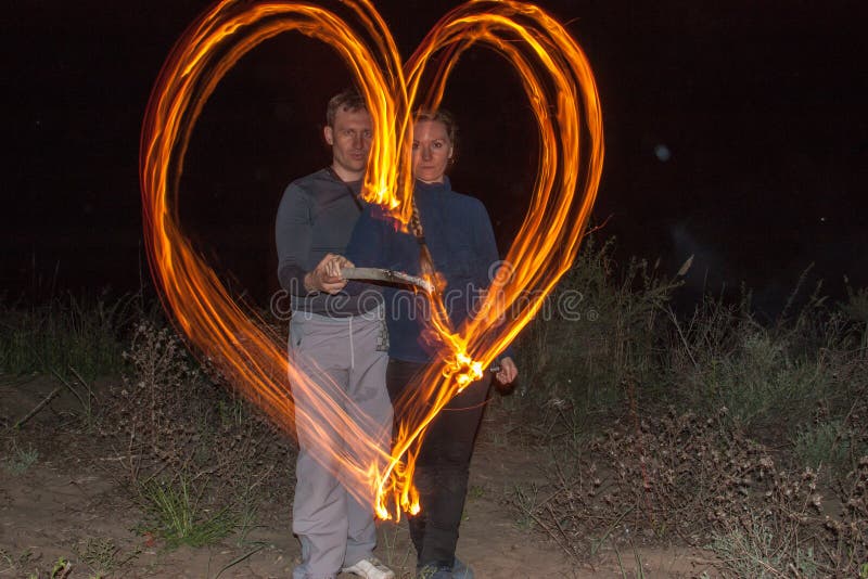 Coppie felici che dipingono le fiamme del cuore di fuoco come simbolo di amore immagini stock Coppie felici che dipingono le fiamme del cuore di fuoco come simbolo di amore immagini stock