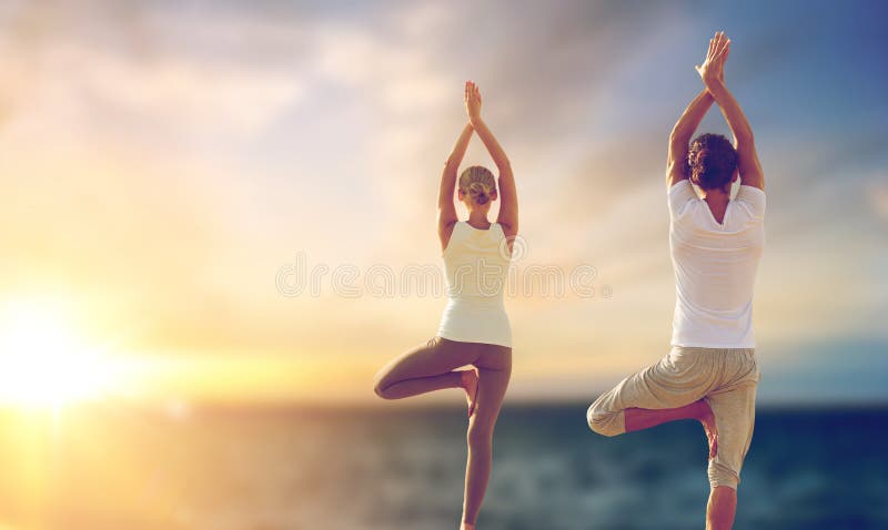 Coppie felici che fanno yoga albero posare sopra il mare fotografia stock libera da diritti Coppie felici che fanno yoga albero posare sopra il mare fotografia stock libera da diritti