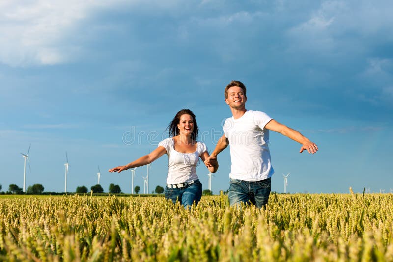 Coppie felici che funzionano sopra il grainfield immagini stock libere da diritti Coppie felici che funzionano sopra il grainfield immagini stock libere da diritti