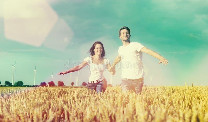 Coppie felici che funzionano sopra il grainfield fotografia stock libera da diritti Coppie felici che funzionano sopra il grainfield fotografia stock libera da diritti