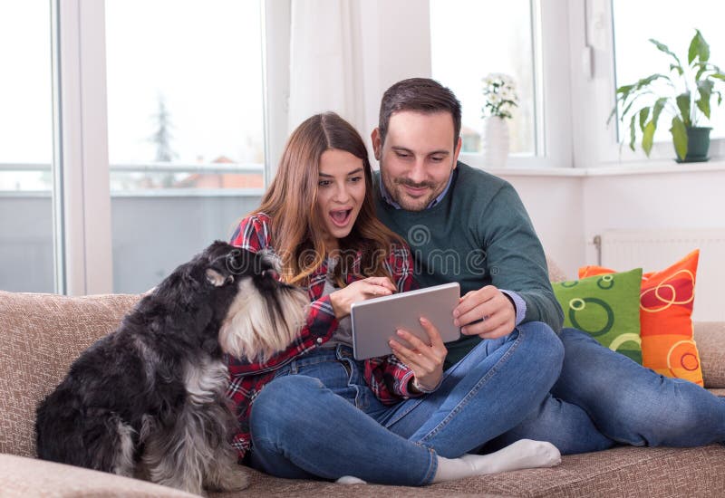 Coppie felici con il cane sul sofà fotografia stock libera da diritti Coppie felici con il cane sul sofà fotografia stock libera da diritti