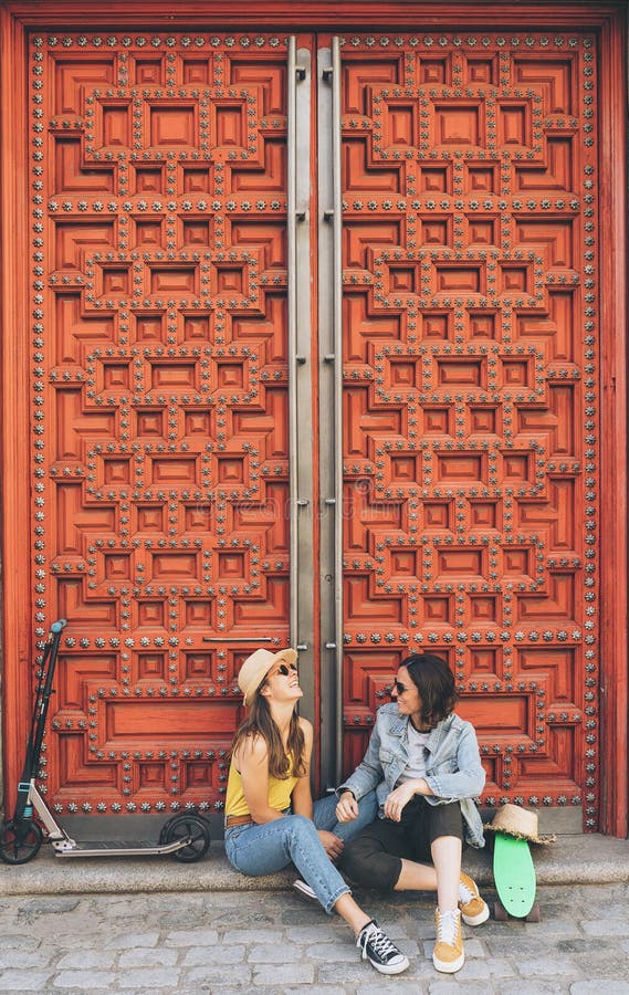 Coppie gay delle giovani donne che guardano e che si sorridono in un fondo rosso della porta La stessi felicità del sesso e conce fotografie stock Coppie gay delle giovani donne che guardano e che si sorridono in un fondo rosso della porta La stessi felicità del sesso e conce fotografie stock