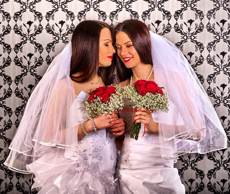 Coppie lesbiche nel baciare nuziale del vestito da nozze