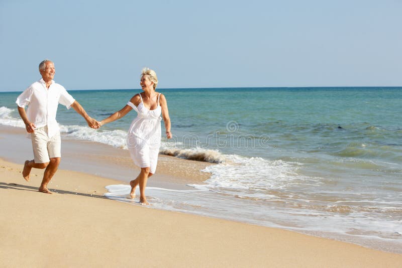 Coppie maggiori che godono della festa della spiaggia al sole fotografia stock libera da diritti Coppie maggiori che godono della festa della spiaggia al sole fotografia stock libera da diritti