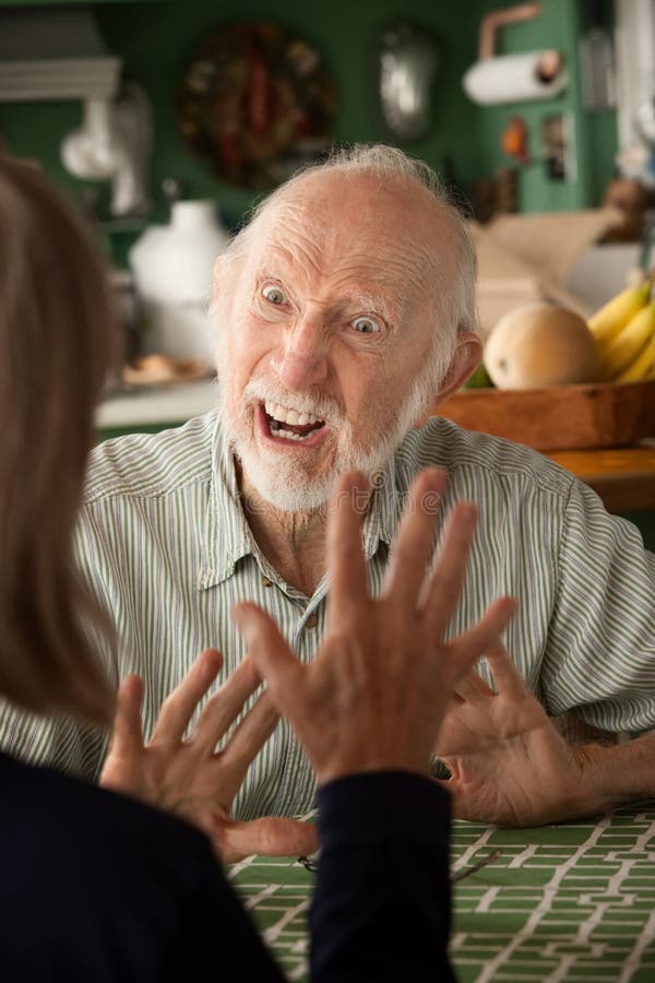 Senior couple at home in kitchen focusing on angry man. Senior couple at home in kitchen focusing on angry man