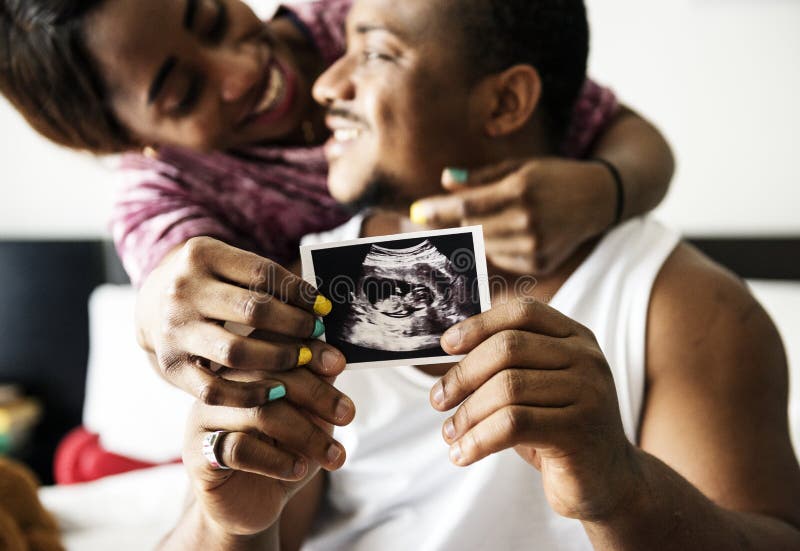 Coppie nere che mostrano la foto di ricerca di ultrasuono del bambino immagine stock Coppie nere che mostrano la foto di ricerca di ultrasuono del bambino immagine stock