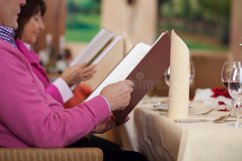 Couple in restaurant sitting at the table and reading the menu. Couple in restaurant sitting at the table and reading the menu