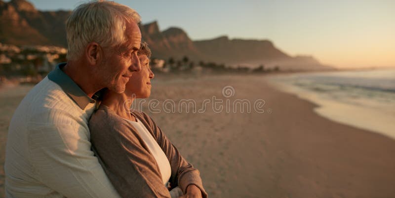 Coppie senior amorose che godono del tramonto alla spiaggia fotografia stock Coppie senior amorose che godono del tramonto alla spiaggia fotografia stock