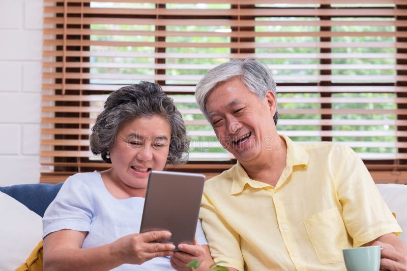 Coppie senior asiatiche imparare a utilizzare calcolo della tavola sul sofà nel salone a casa senior con il lfiestyle di tecnolog