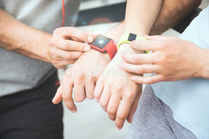 Coppie sportive che dividono i dati di allenamento dai loro smartwatches fotografia stock Coppie sportive che dividono i dati di allenamento dai loro smartwatches fotografia stock