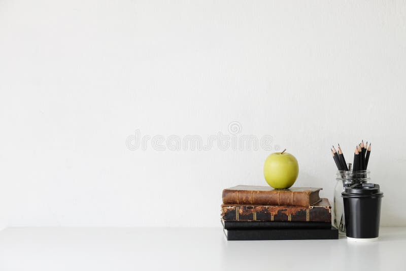 Copy space of books, green apple, coffee cup and pencil on white