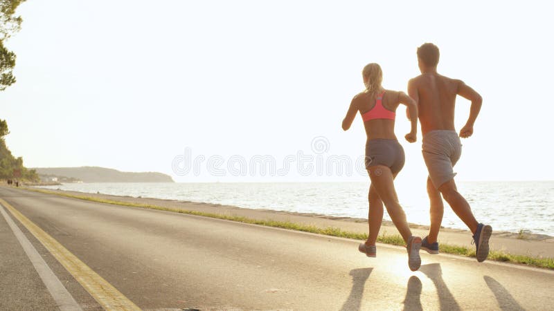 COPY SPACE Bright sun rays shine down on active boyfriend and girlfriend running royalty free stock photo