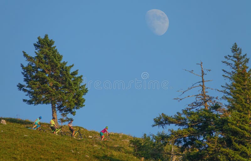 COPY SPACE: Moon rises above the tourists on bikes observing the evening nature. stock images