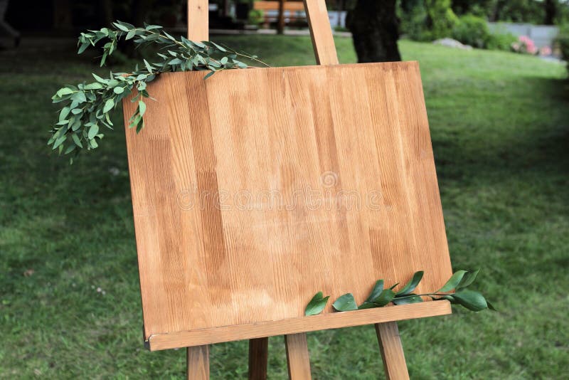 Wooden easel with a board. On the board written white paint - We