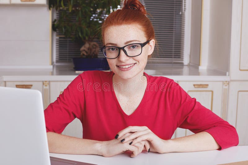Copywriter Redhead молодой умелый женский с freckled кожей, носит квадратные зрелища, работает на родовой компьтер-книжке, находя стоковые фото Copywriter Redhead молодой умелый женский с freckled кожей, носит квадратные зрелища, работает на родовой компьтер-книжке, находя стоковые фото