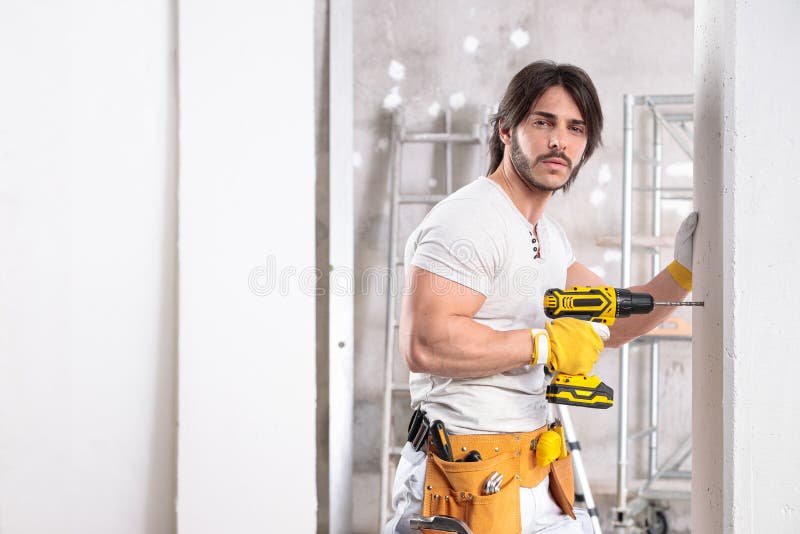 Coqueto constructor muscular que trabaja con un taladro imagen de archivo libre de regalías