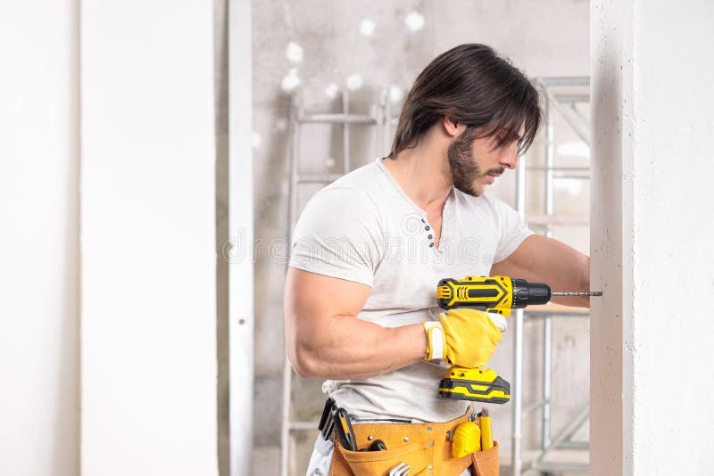 Coqueto constructor muscular que trabaja con un taladro fotos de archivo libres de regalías