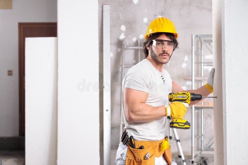 Coqueto constructor muscular que trabaja con un taladro foto de archivo