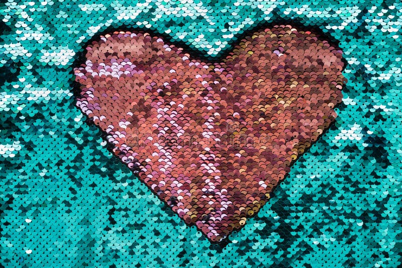Coral heart made of sequins on turquoise background. 