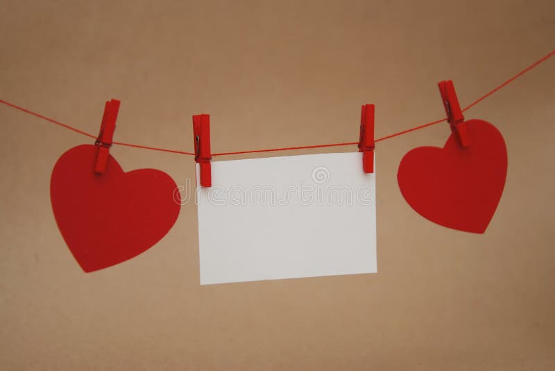 Corazones de papel rojos que cuelgan en secuencia con el mini Pin de ropa sobre el fondo neutral de marfil Día del `s de la tarje imágenes de archivo libres de regalías Corazones de papel rojos que cuelgan en secuencia con el mini Pin de ropa sobre el fondo neutral de marfil Día del `s de la tarje imágenes de archivo libres de regalías