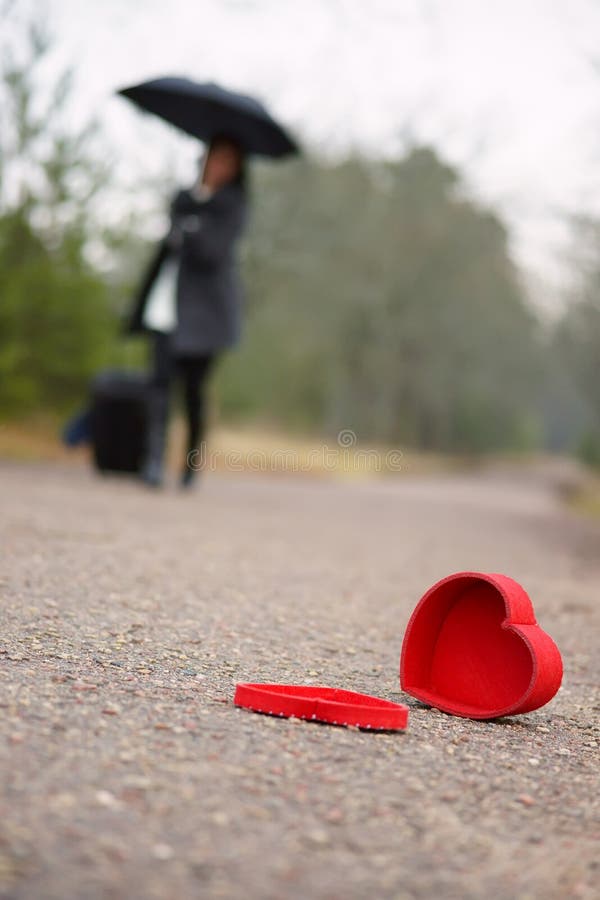 Corazón en el camino y la mujer con equipaje y el paraguas en el fondo imagen de archivo Corazón en el camino y la mujer con equipaje y el paraguas en el fondo imagen de archivo