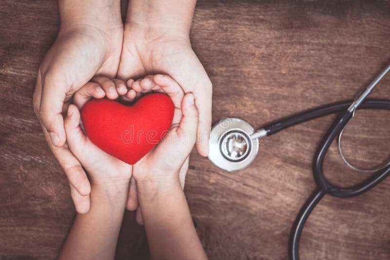 Corazón rojo en las manos de la mujer y del niño y con el estetoscopio del ` s del doctor fotos de archivo libres de regalías Corazón rojo en las manos de la mujer y del niño y con el estetoscopio del ` s del doctor fotos de archivo libres de regalías