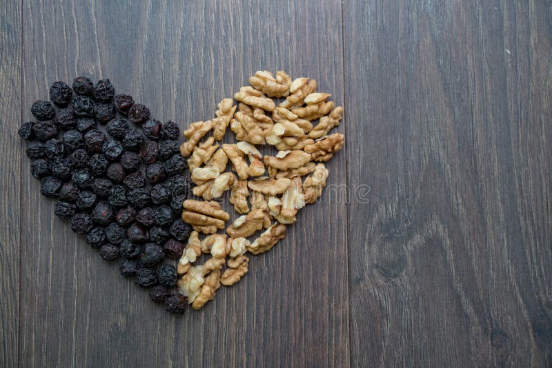 Heart of dried cherries and nuts on wooden table , top view. Heart of dried cherries and nuts on wooden table , top view