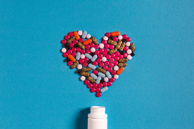 Coração do símbolo do medicamento dos comprimidos da cor no fundo azul Conceito da medicina da faculdade criadora